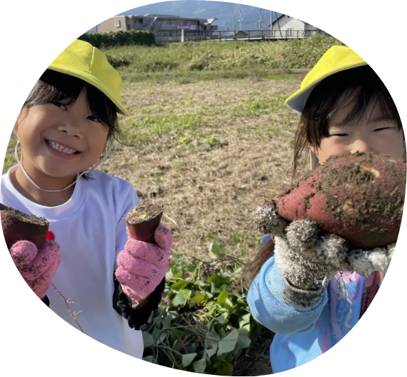さつまいもを抱えるにこにこの笑顔の園児